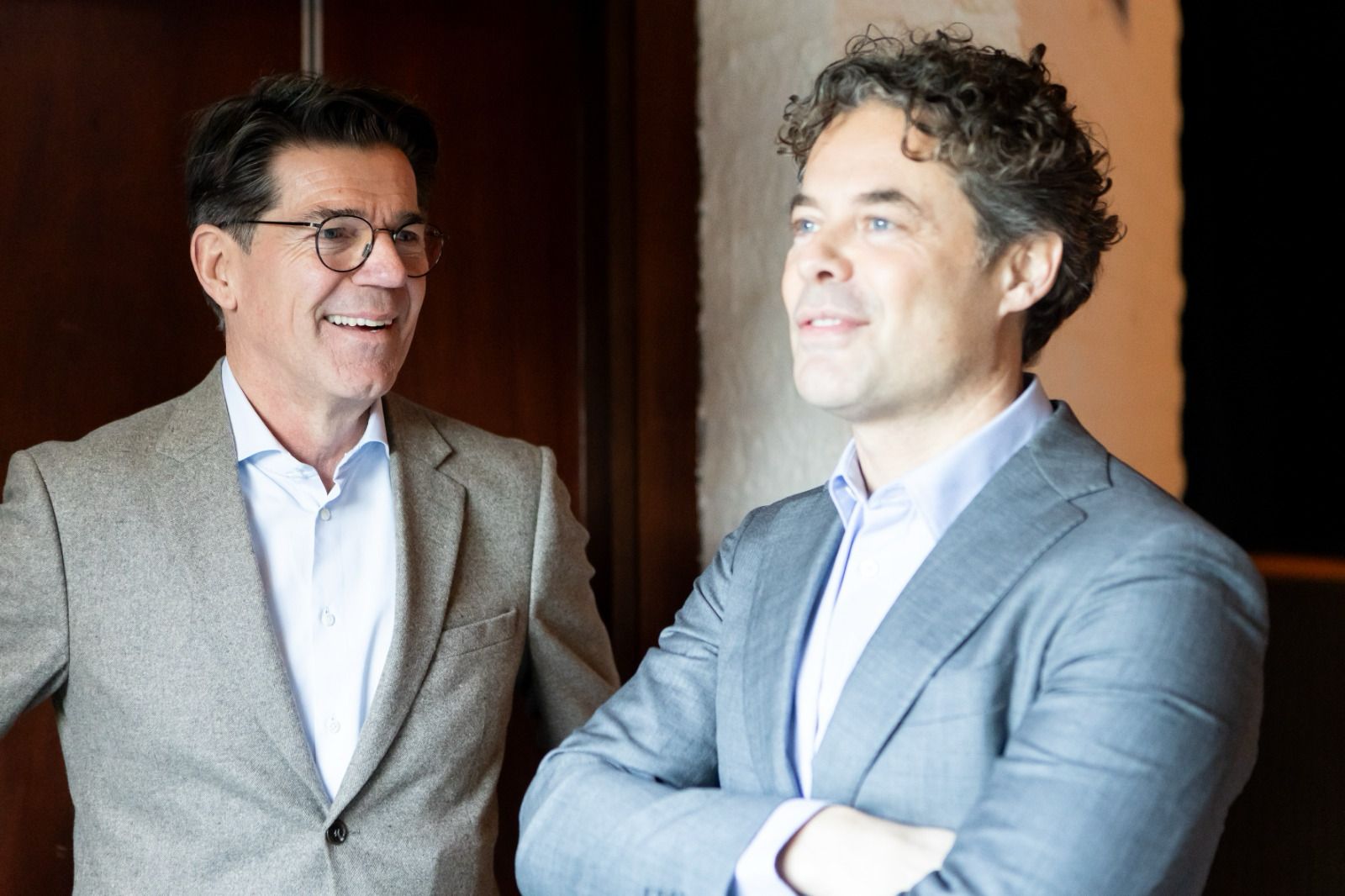 Twee mannen in pak hebben een geanimeerd gesprek in een zakelijke omgeving.