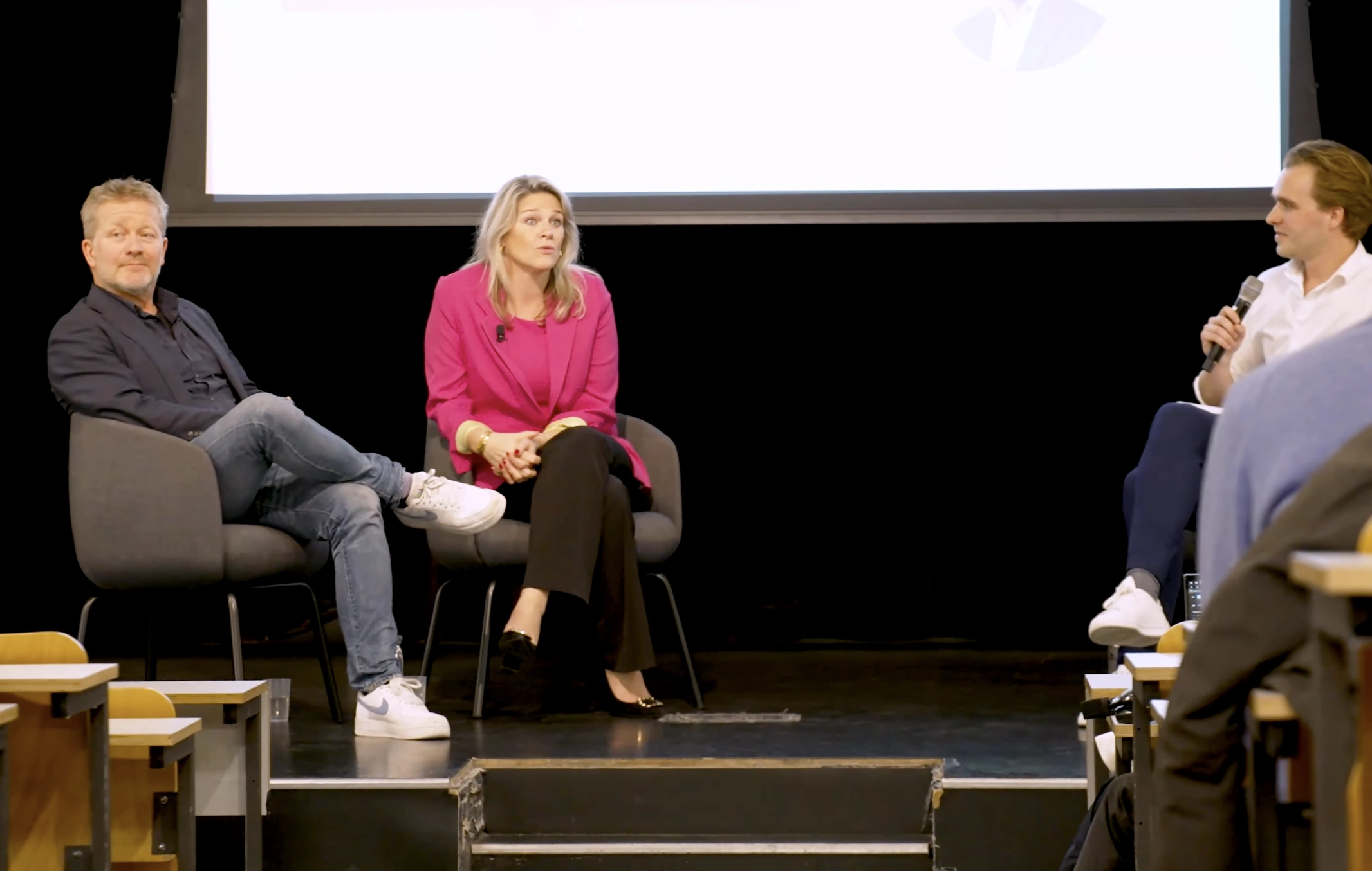 Paneldiscussie tijdens de AM college tour met drie sprekers zittend op een podium.