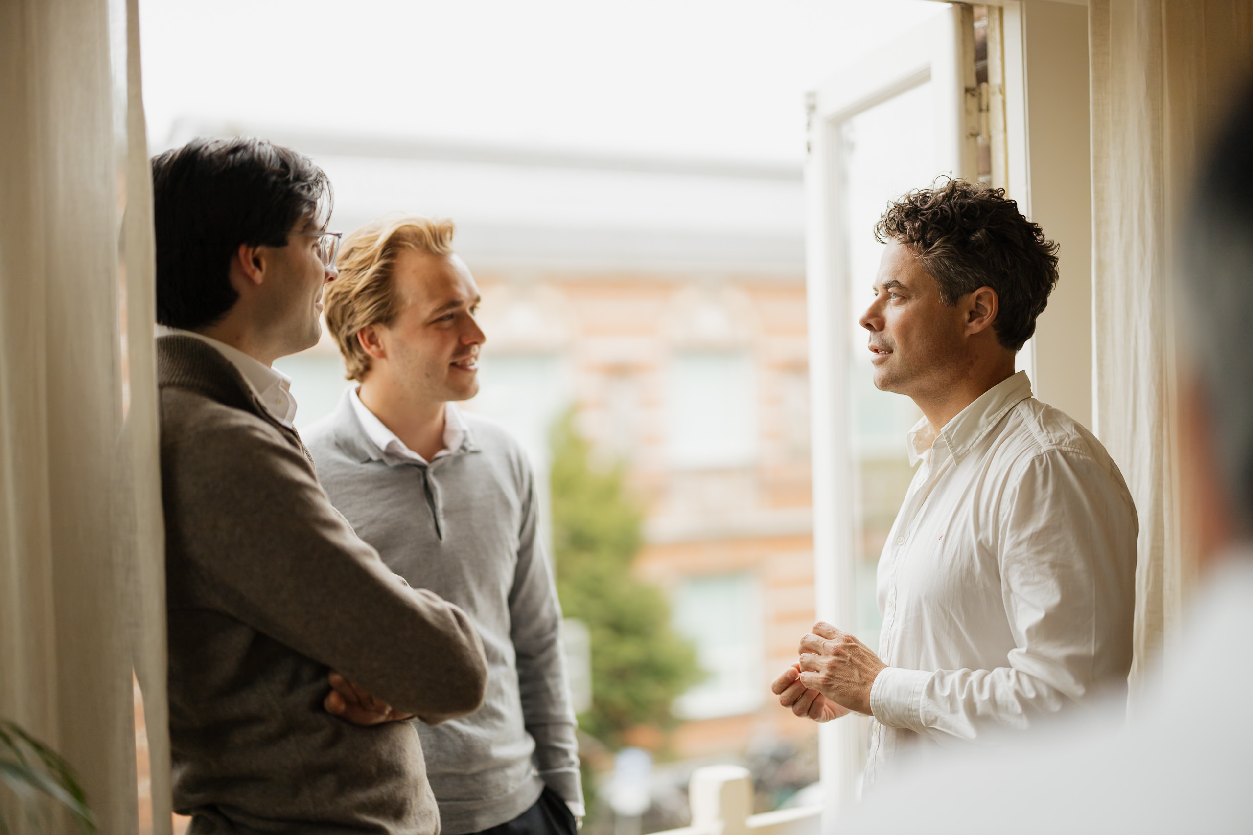 Drie mannen in gesprek bij een open deur tijdens een bijeenkomst van de Dutch Fund and Asset Management Association.