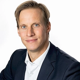 Portret van Anne, bestuurslid van DUFAS, in pak voor een witte achtergrond.