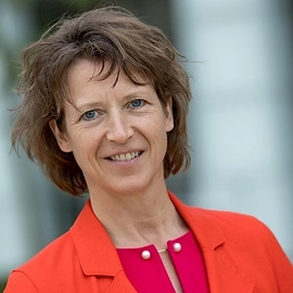 Portret van Geraldine, bestuurslid van DUFAS, in een feloranje jasje.