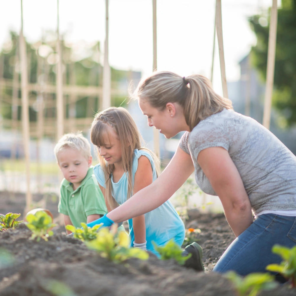 Een vrouw en twee kinderen werken samen in een moestuin voor een leefbare wereld.
