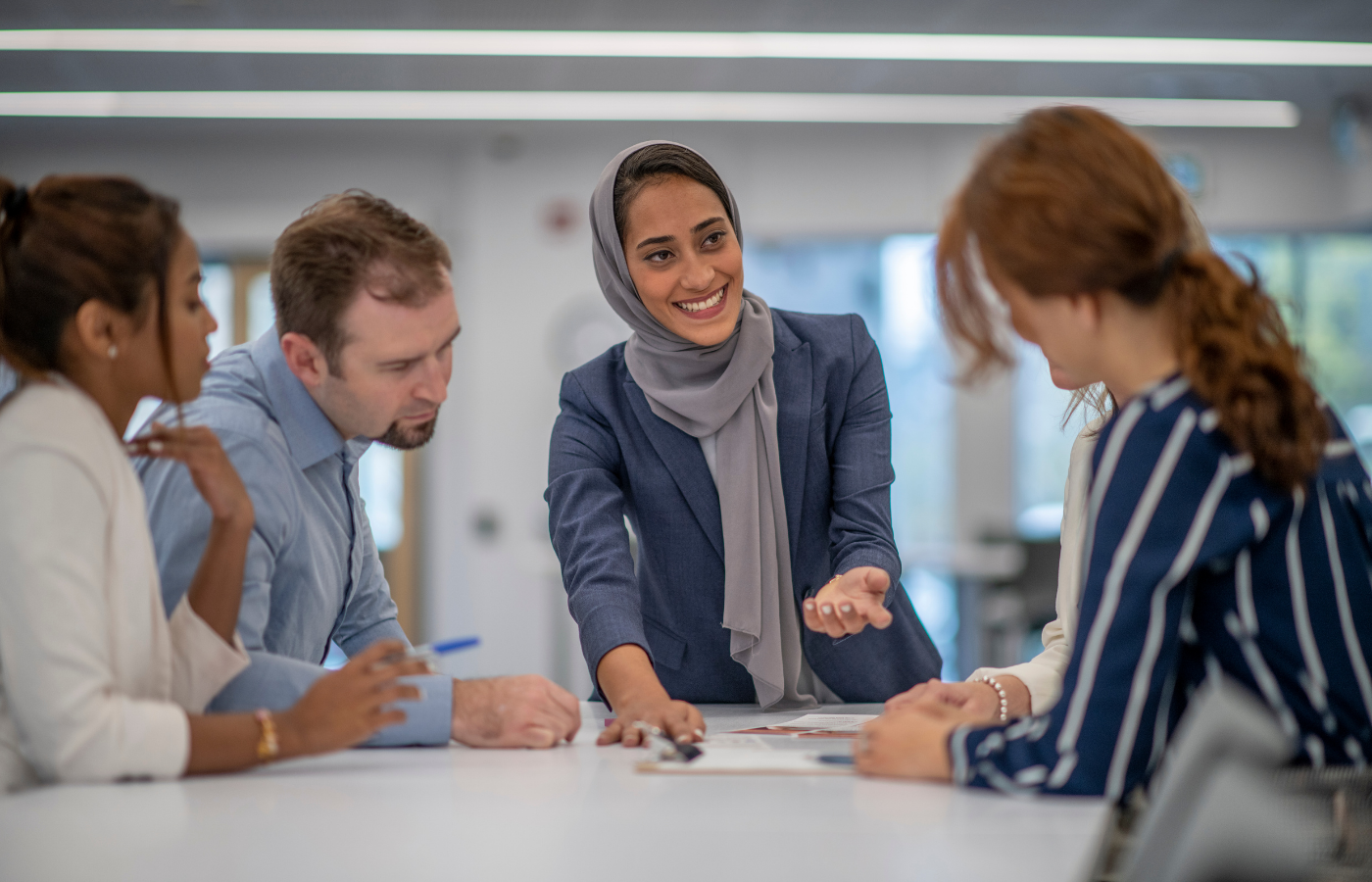 Zakenvrouw leidt een enthousiaste discussie met collega's rond een vergadertafel over een sterke samenleving en economie.