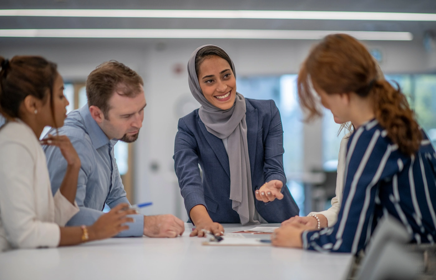 Zakenvrouw leidt een enthousiaste discussie met collega's rond een vergadertafel over een sterke samenleving en economie.